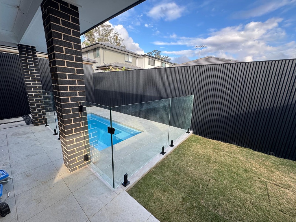 Glass pool fence with black spigots and self-closing gate