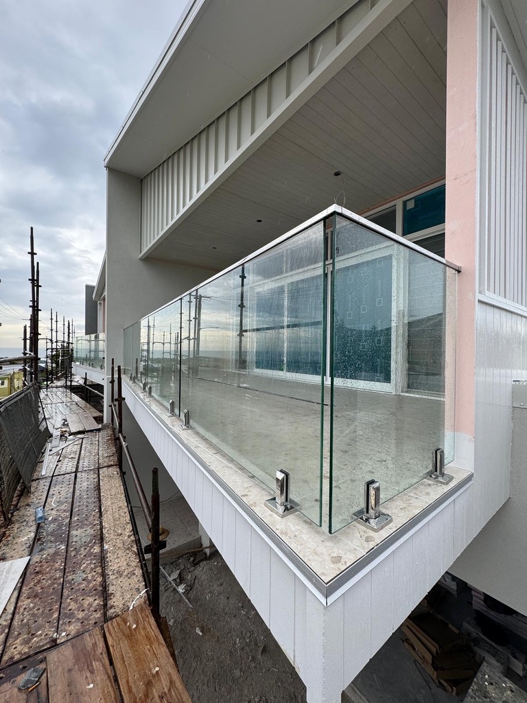 Frameless glass balcony balustrade with chrome hardware, coastal exposure