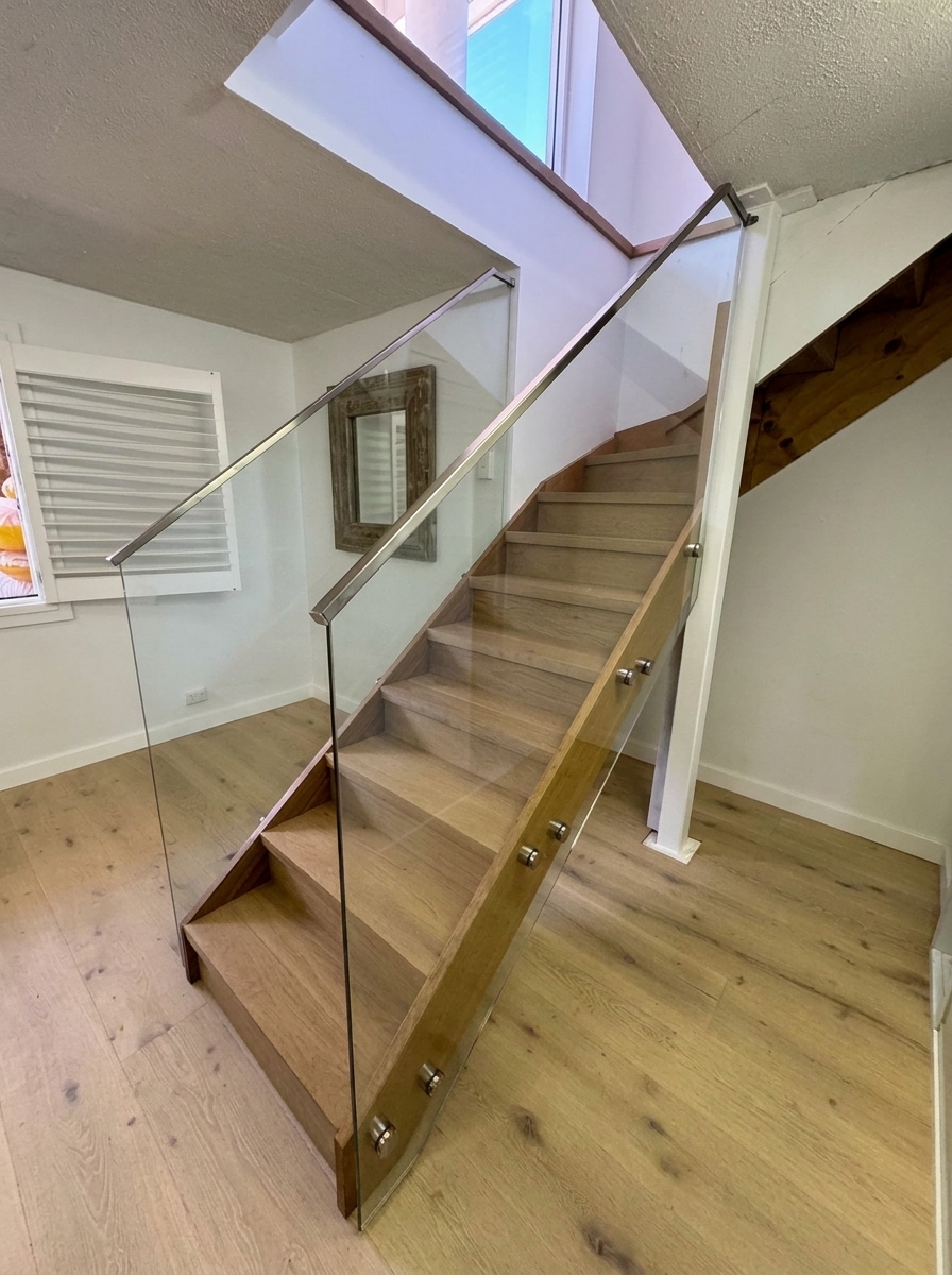 Frameless glass stair balustrade with standoff fixings and oak treads