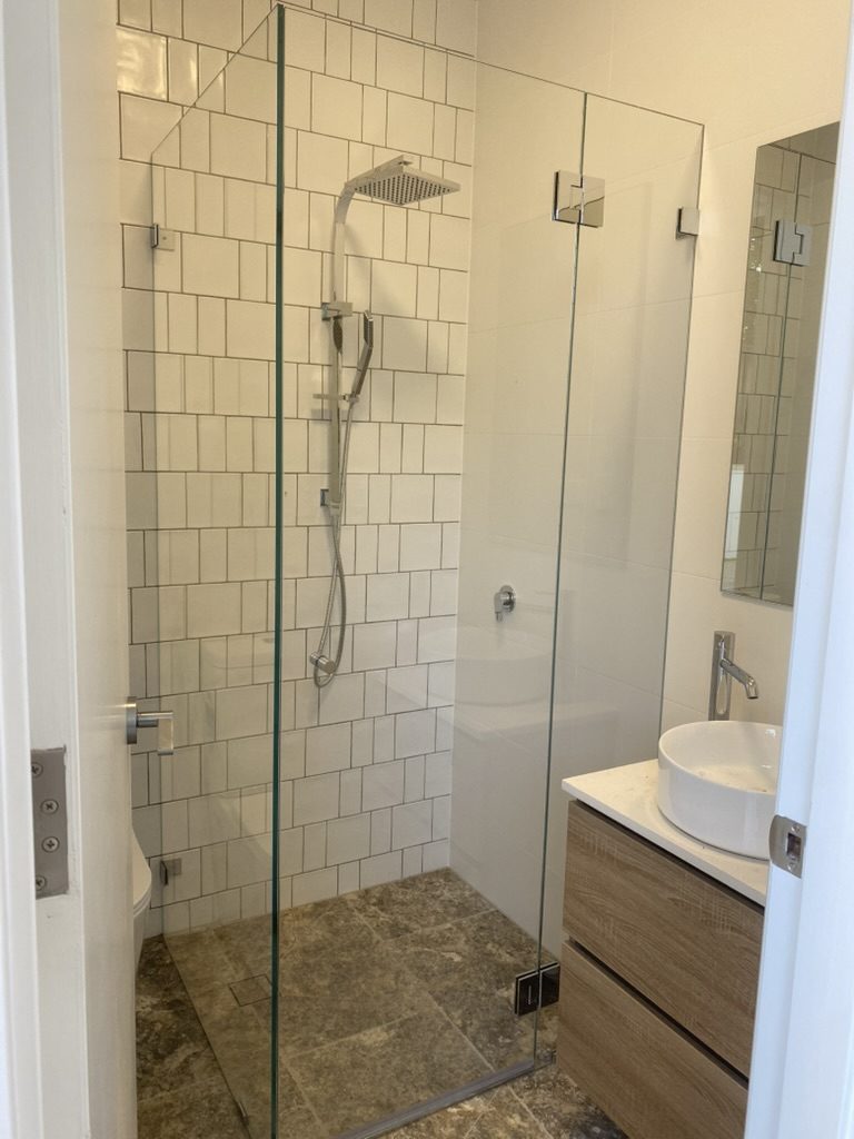 Frameless hinged glass shower with chrome hardware and white subway tile