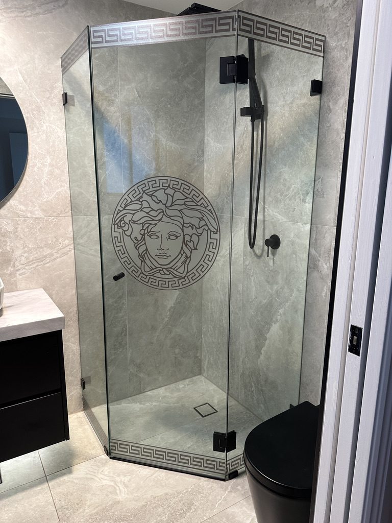Frameless neo-angle shower with Versace Medusa etched glass and matte black hardware