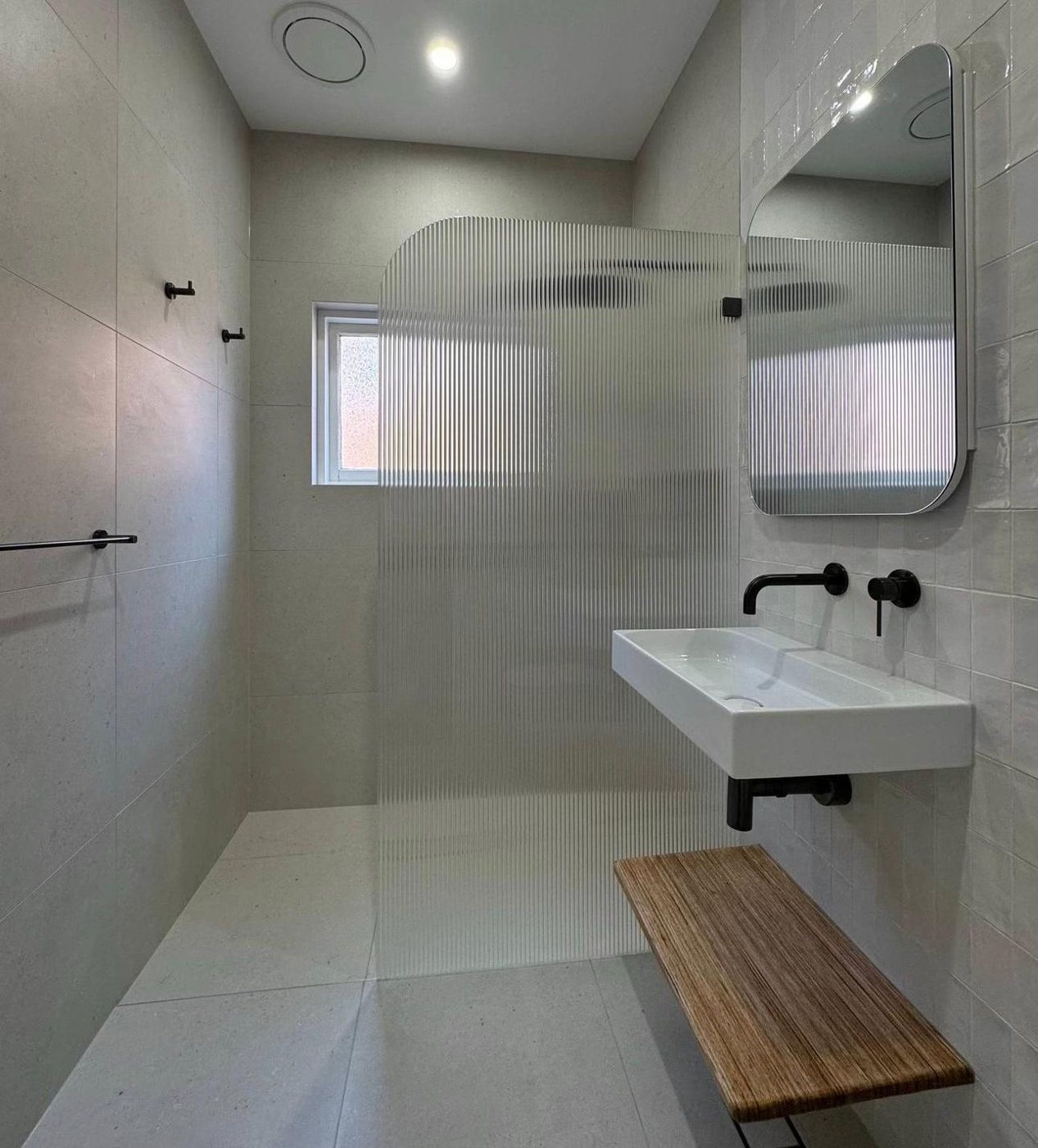 Curved arched fluted-glass frameless shower screen with a floating vanity