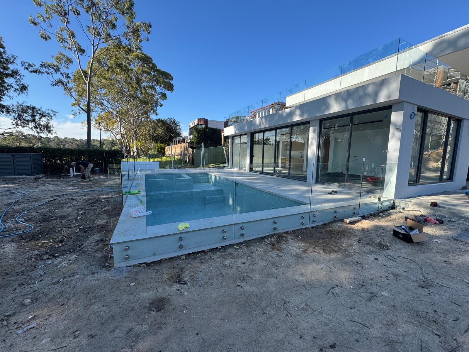 Frameless glass pool fence on deck with matte black spigots