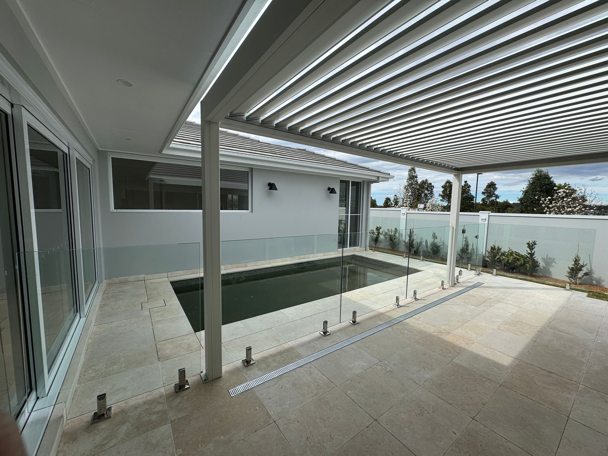 Curved frameless glass pool fence with chrome spigots
