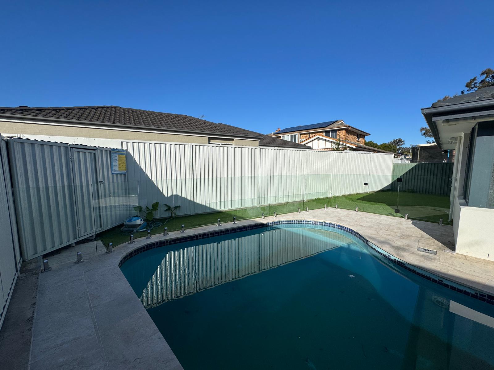 Frameless glass pool fence with chrome standoff fixings on new-build property